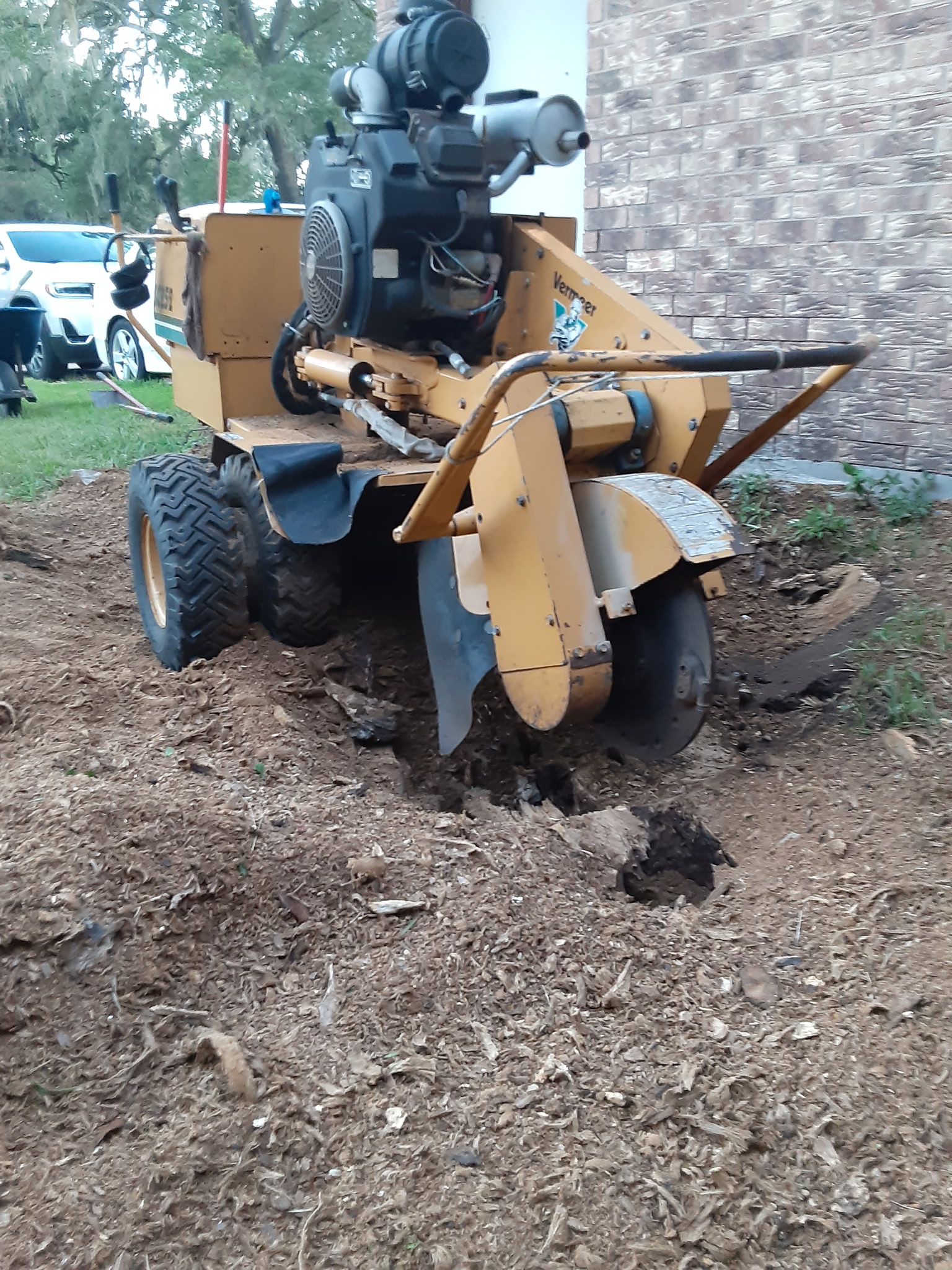 Stump removal in progress near a brick home